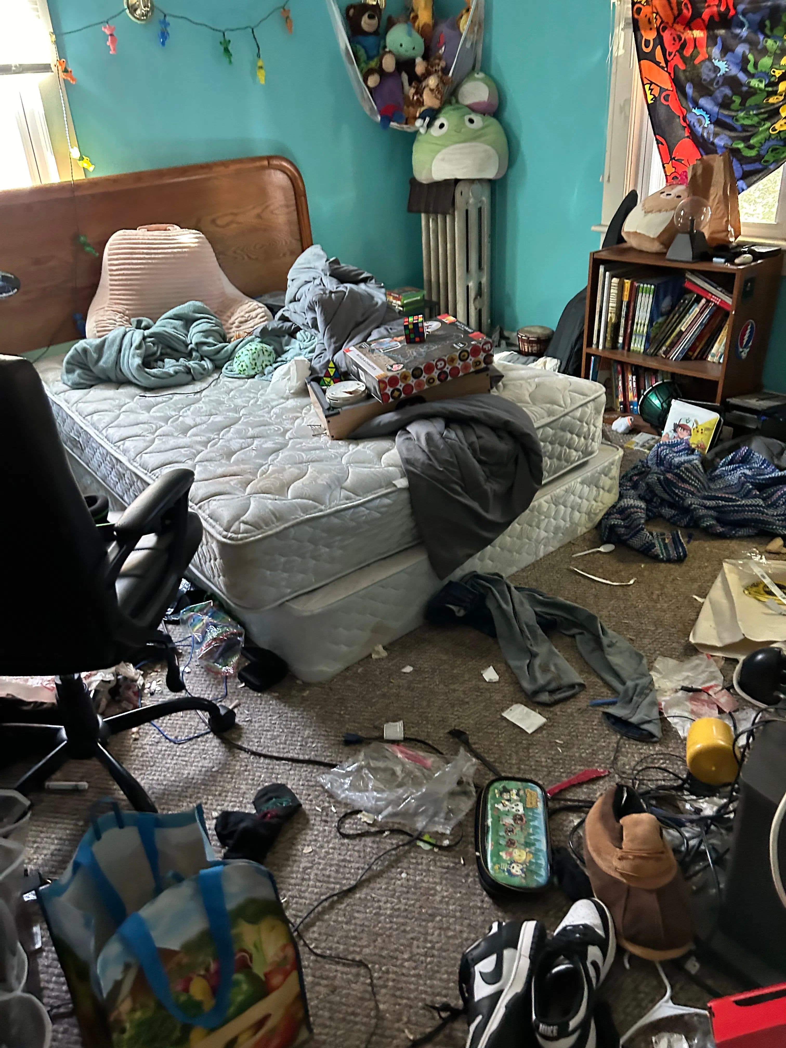 Cluttered bedroom with messy bed, scattered clothes, and disorganized belongings.